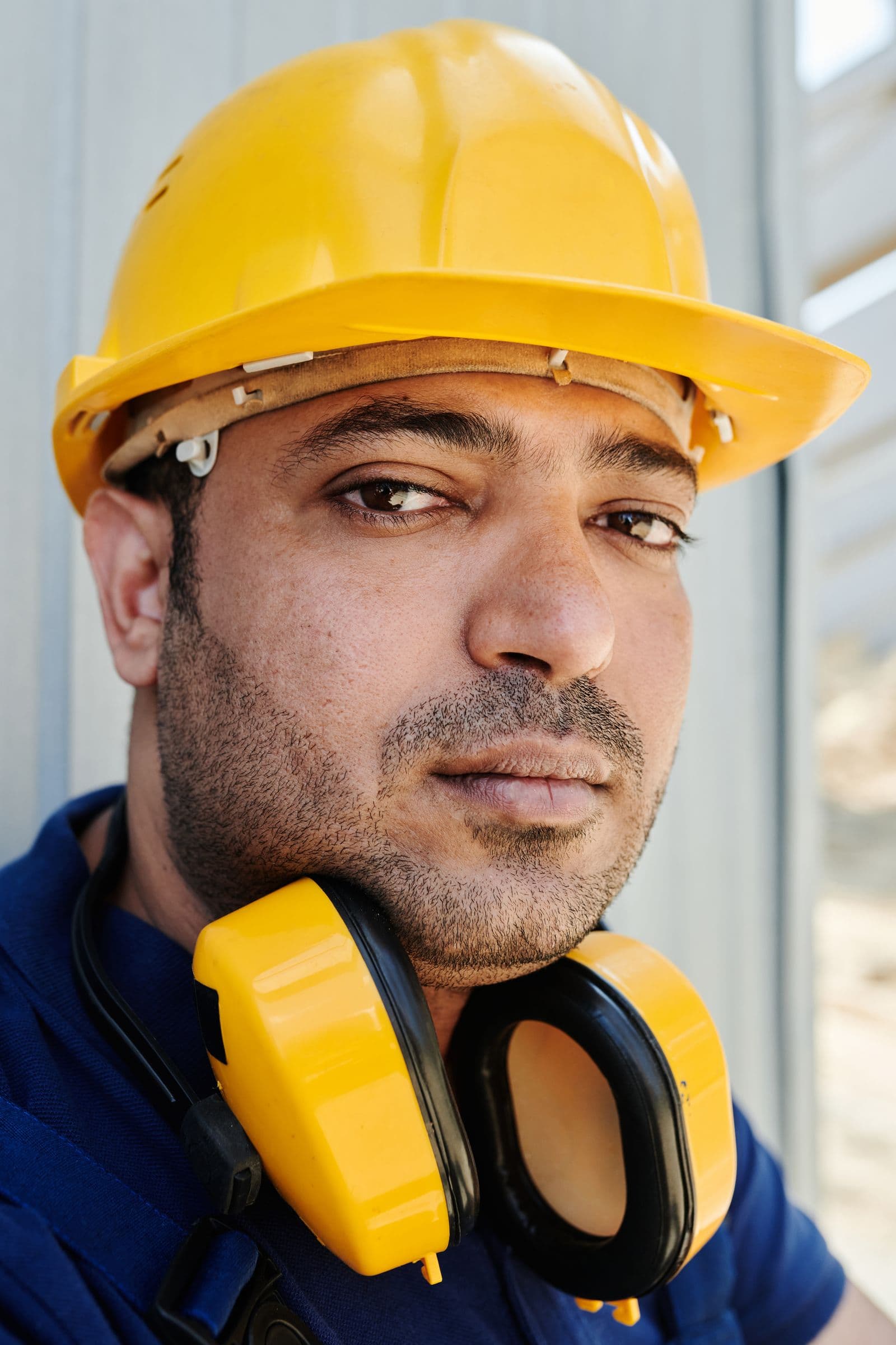 Construction worker wearing a hard hat with ear protection resting around his neck