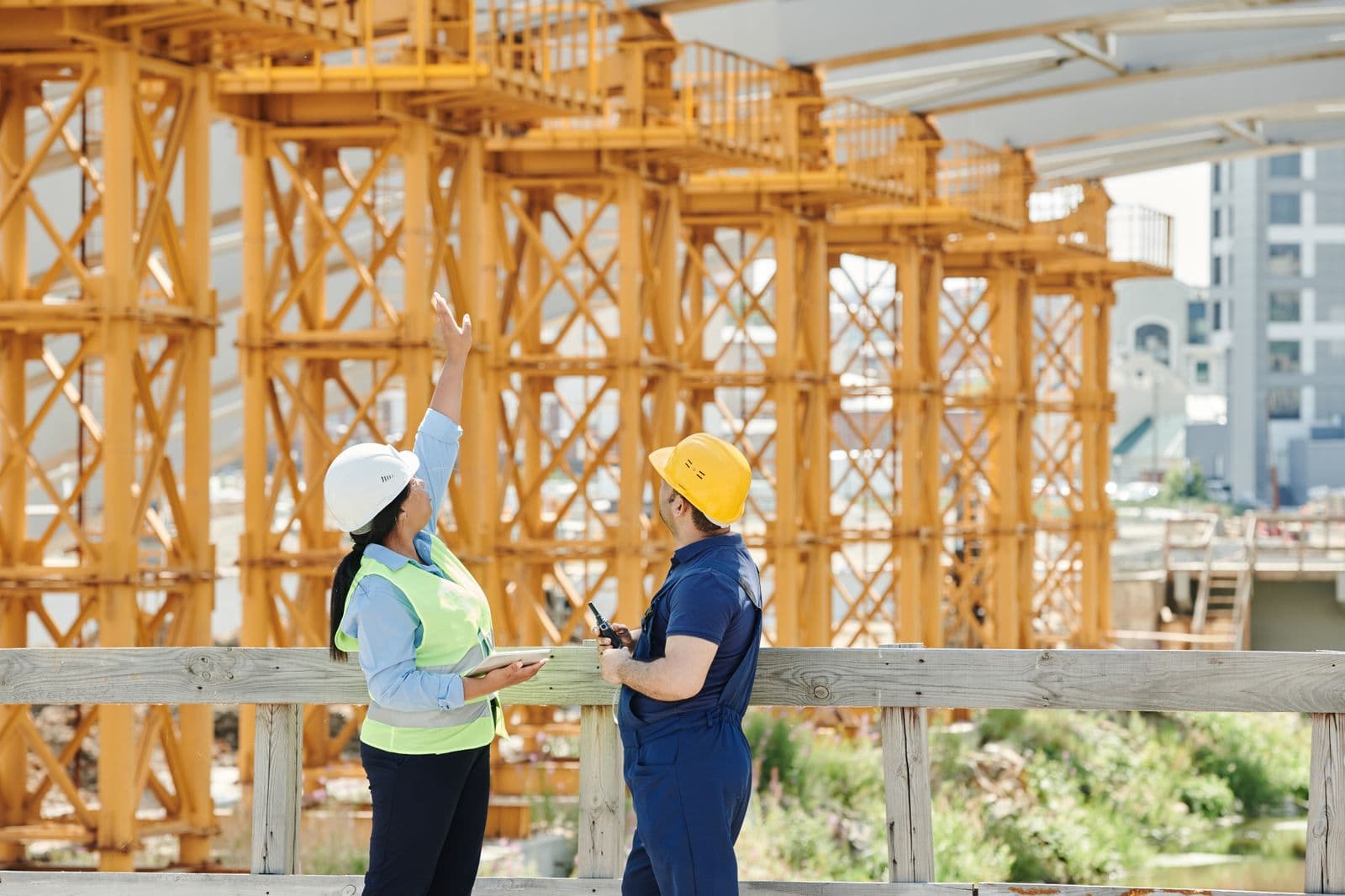 Two construction workers in hard hats discussing a plan at a jobsite