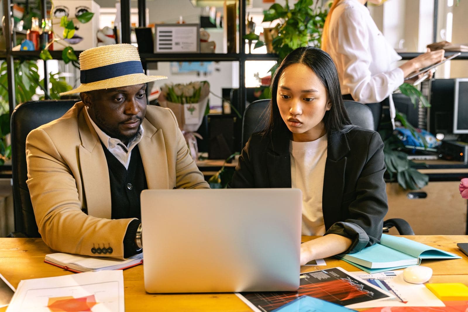 Two coworkers collaborating on a laptop in a modern office
