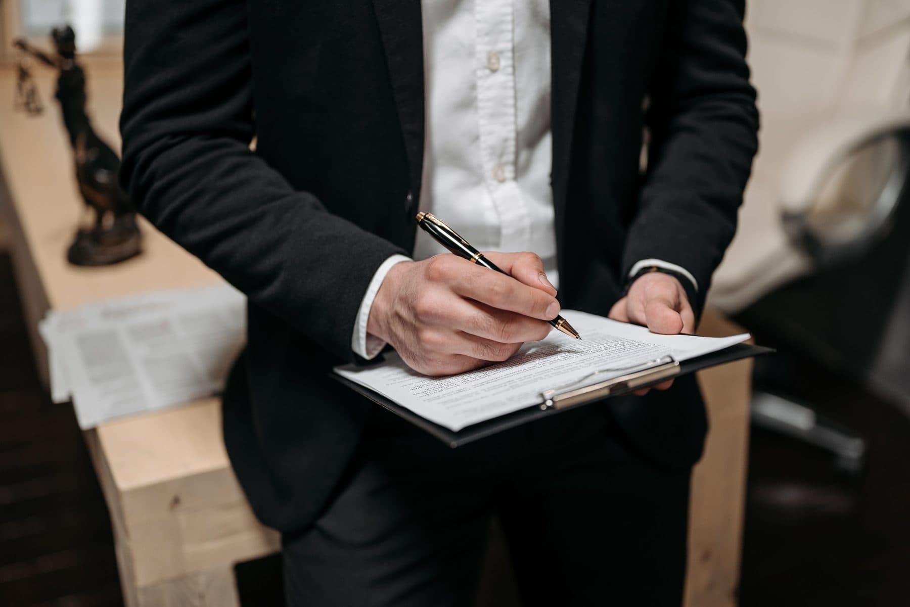 A person in an office reviewing and signing a document on a clipboard