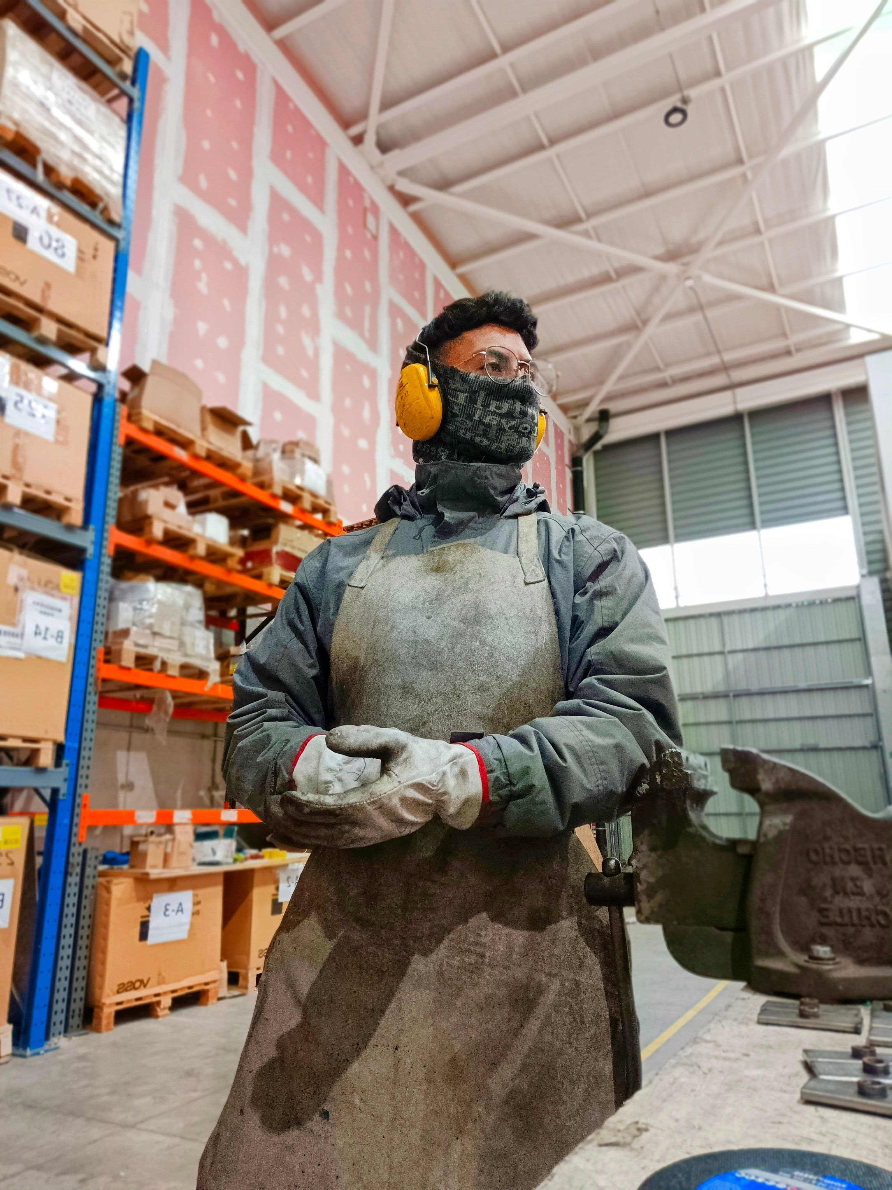 Worker wearing protective apron and noise-cancelling headphones in an industrial workshop