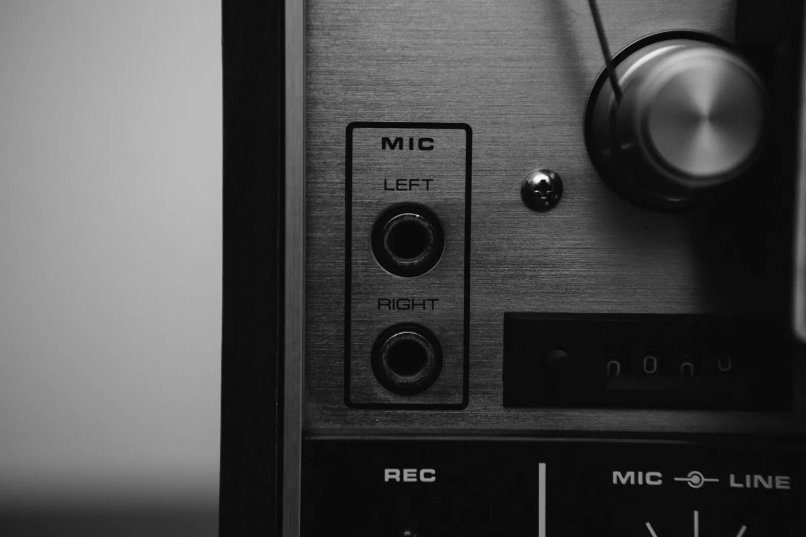 A black and white close-up of a vintage audio mixer with microphone inputs