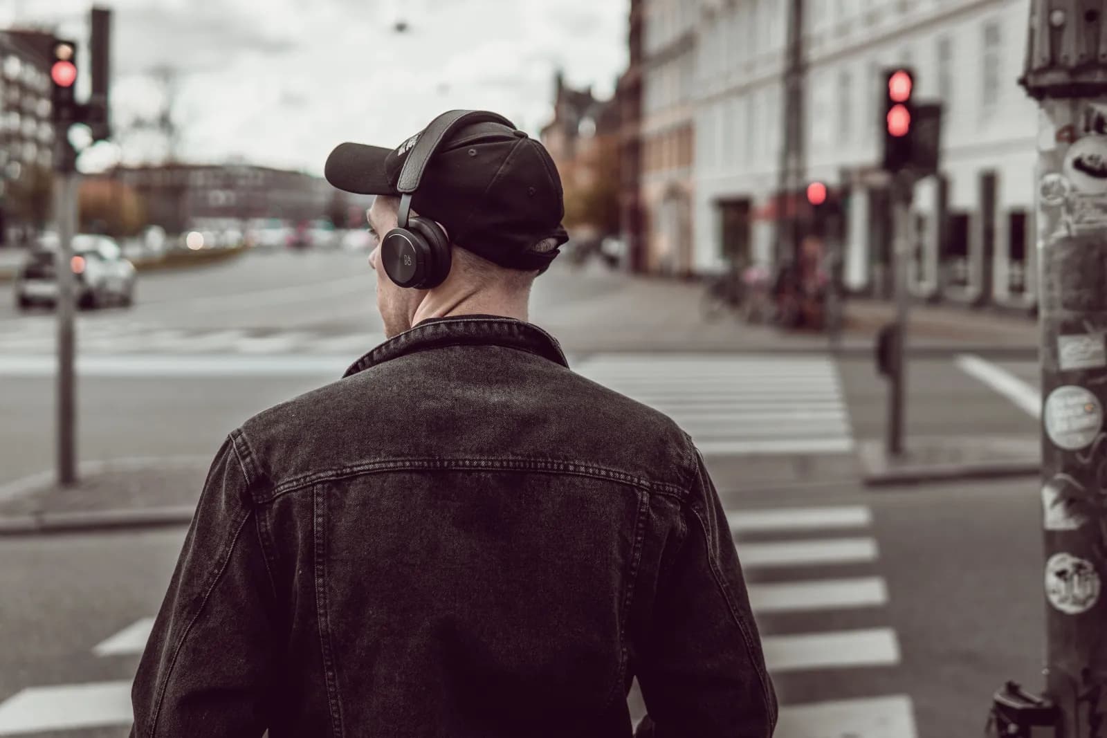 A man wearing headphones and listening to audio while walking through a city crosswalk