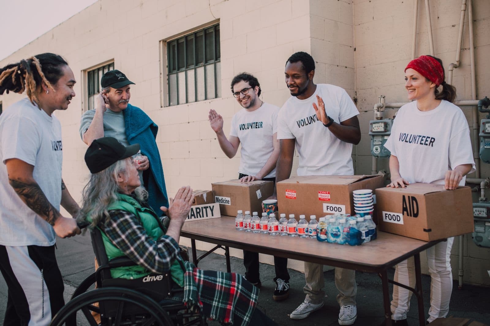 Volunteers helping a person in a wheelchair outdoors, the kind of program moment nonprofits already document but rarely turn into audio