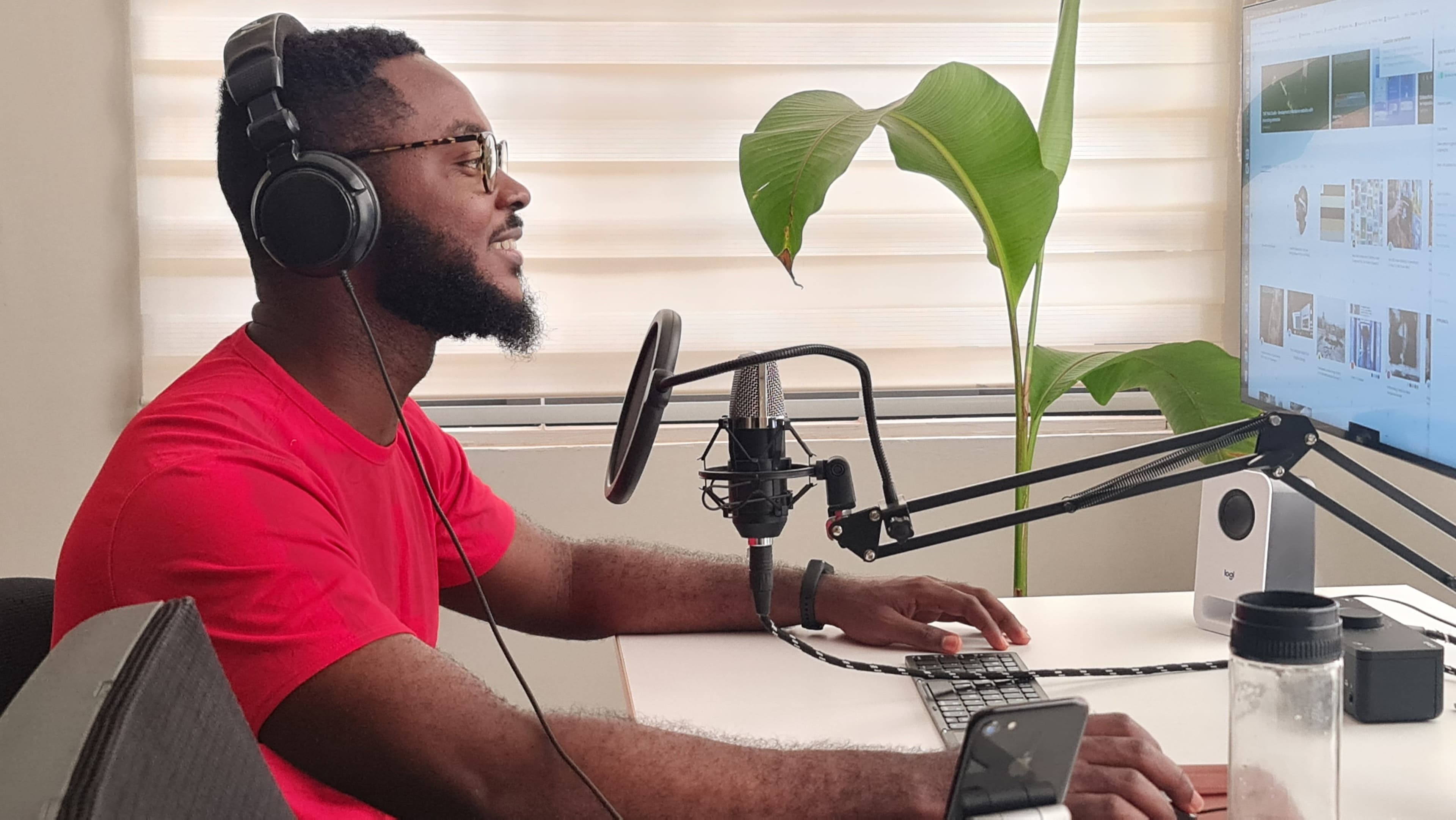 Man recording a podcast in a home studio with a microphone, headphones, and a laptop