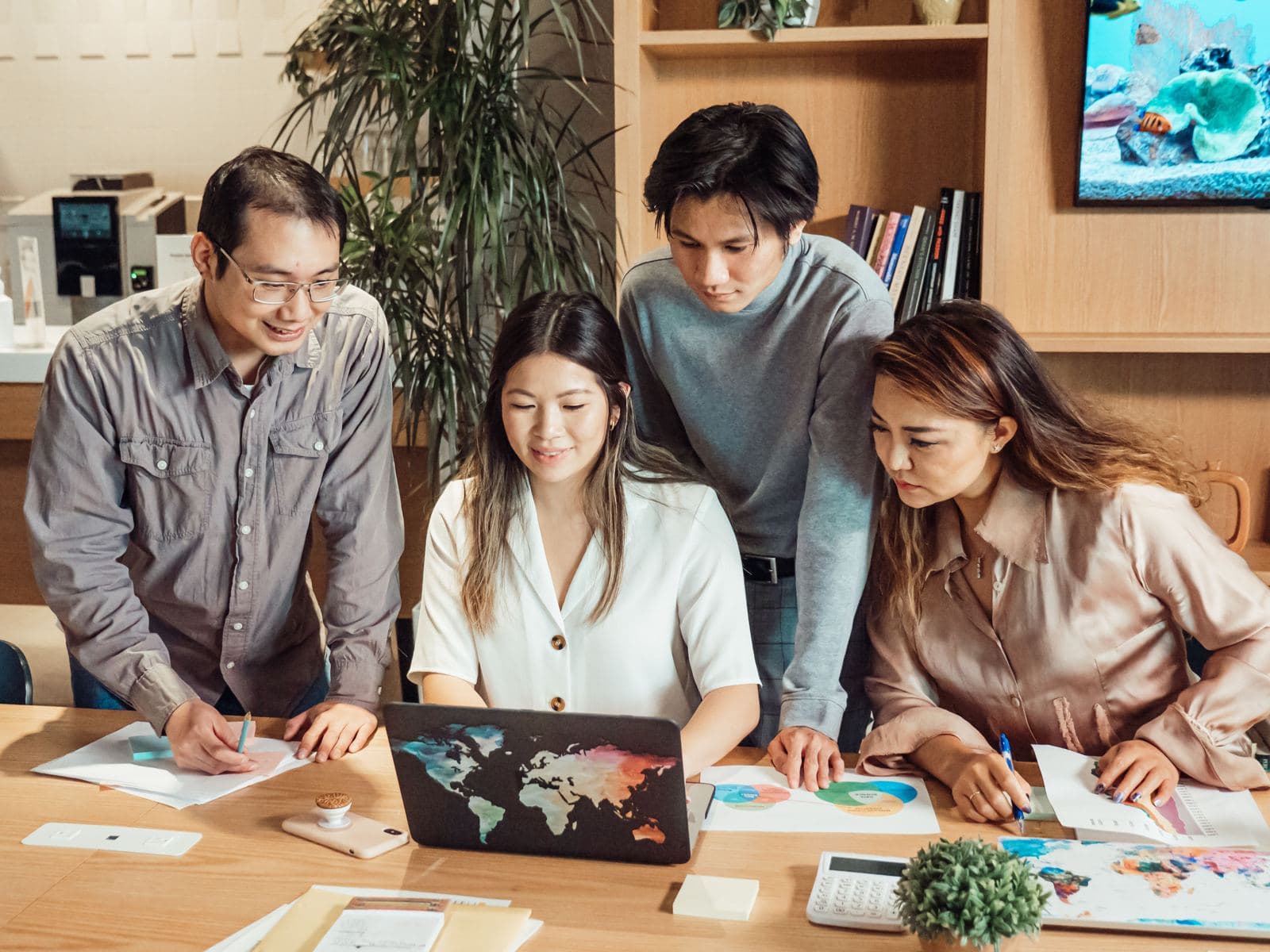 A diverse group of professionals meeting around a laptop in an office