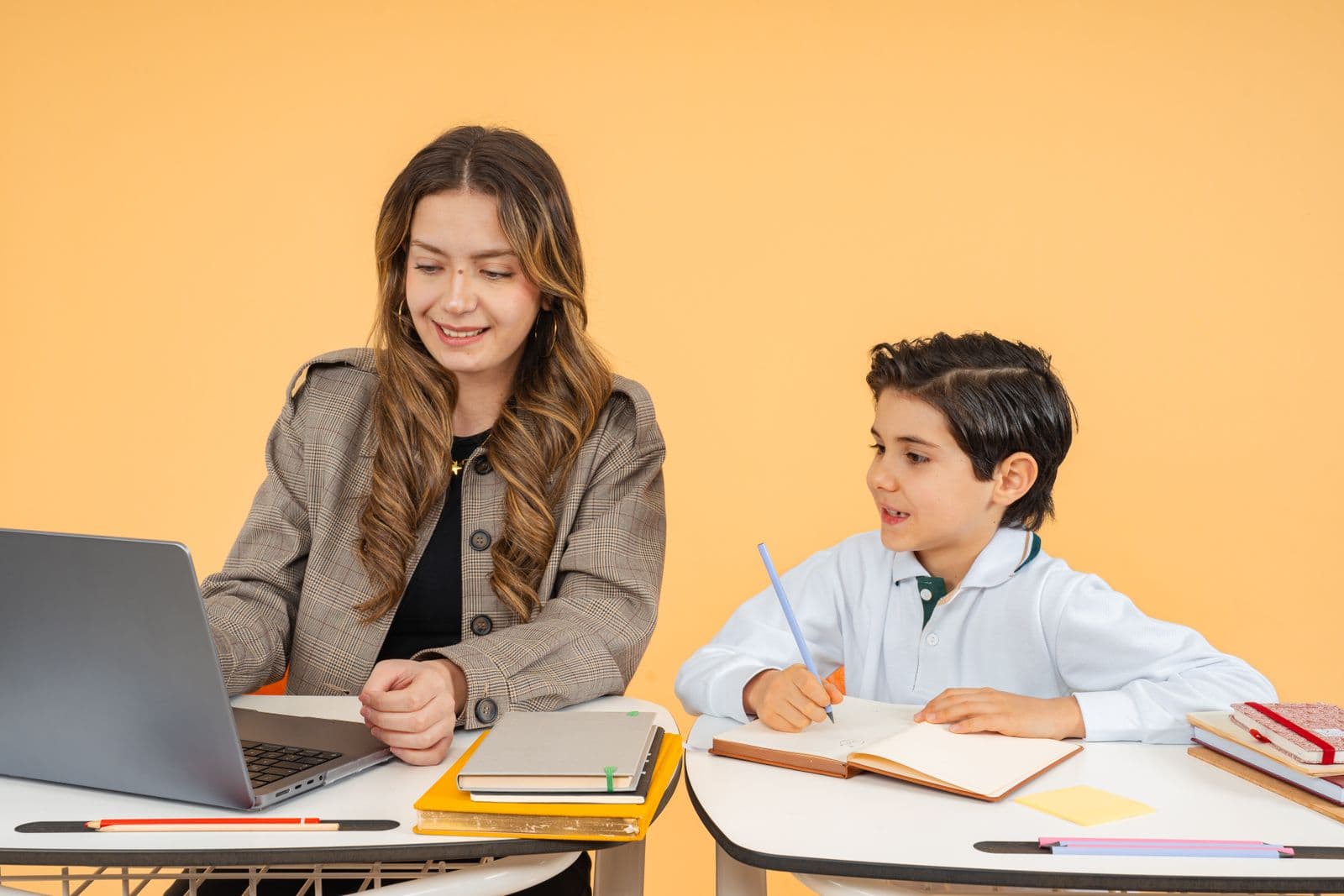 A teacher helping a student with schoolwork on a laptop