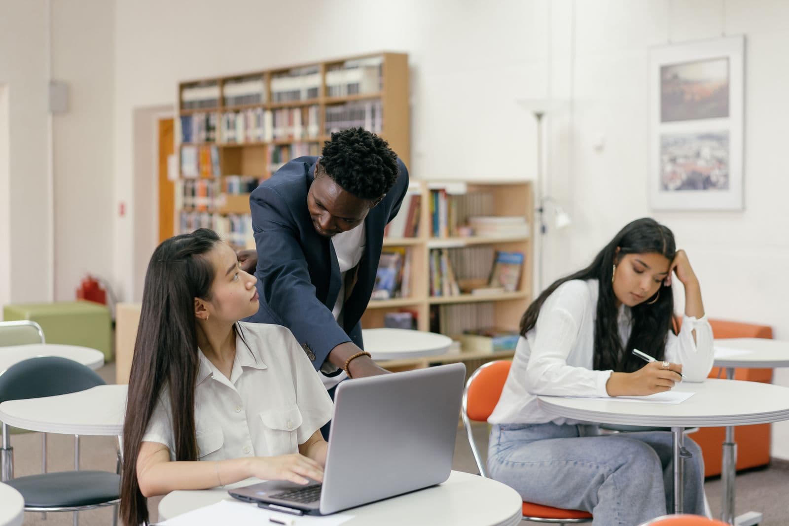 A teacher pointing at a student's laptop screen during class