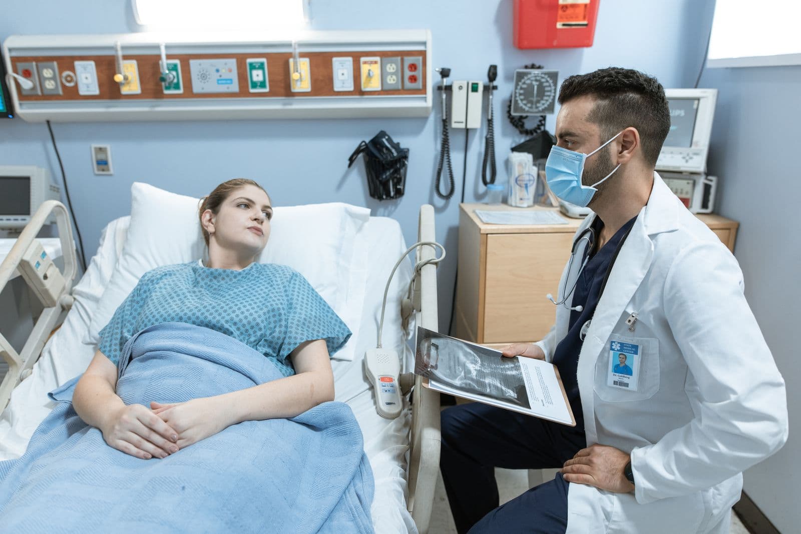 A nurse talking with a patient lying in a hospital bed