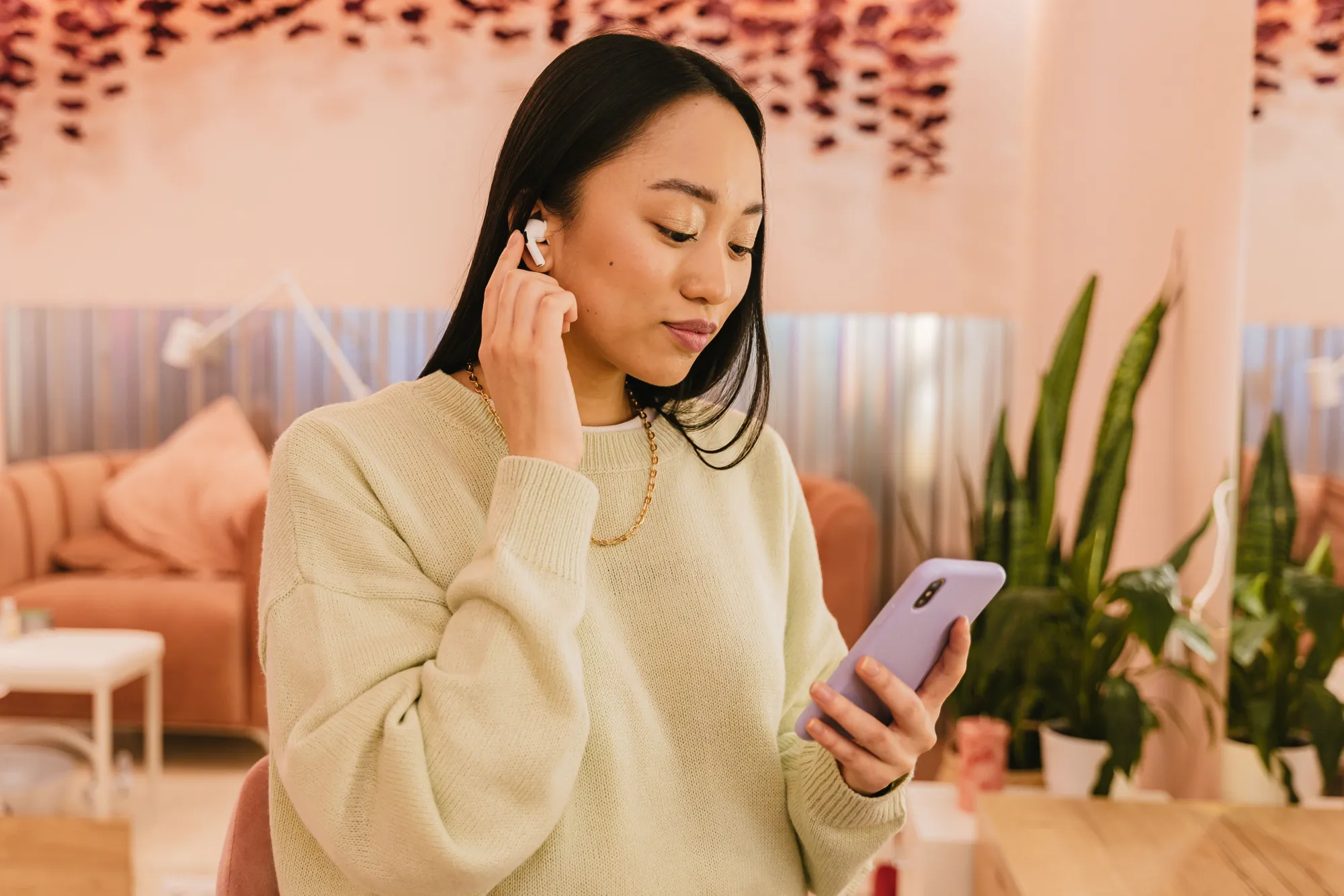 A woman listening to audio through wireless earphones while using her phone